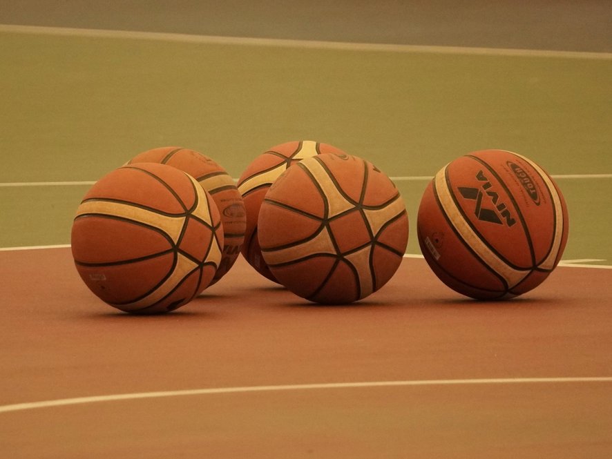 Basketbälle liegen auf dem Boden einer Turnhalle